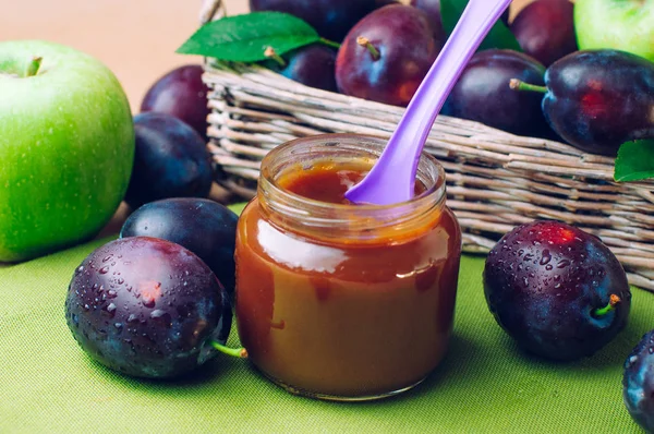 Kavanozlu bebek maması erik püresi ve taze eriklerin yanında kaşık.