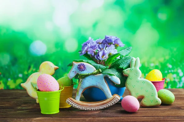 Bemalte Eier, Oster-Lebkuchen und Primeln auf Holz — Stockfoto