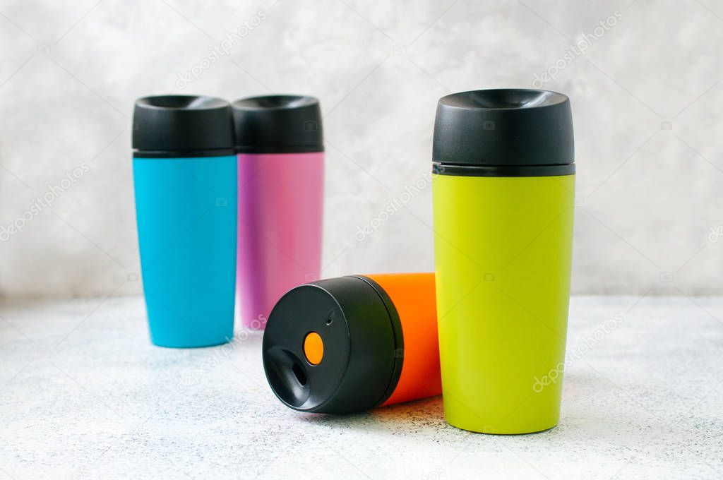 Four thermos mugs on grey background with copy space