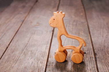 Tekerlekler üzerinde oyuncak zürafa taşralı ahşap arka planda ve metin için boş alan var..