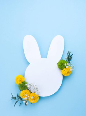 Beyaz kağıttan paskalya tavşanı açık mavi arka planda çiçekler