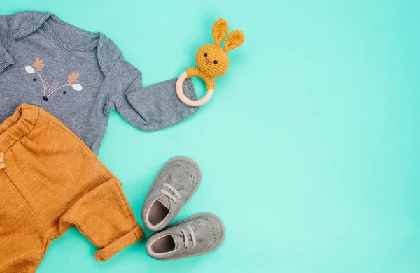 Pasgeboren baby kleding en konijn bonenzak op turquoise achtergrond — Stockfoto