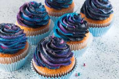 Galaksi krem şantili kapkeklerin yakın plan resmi.