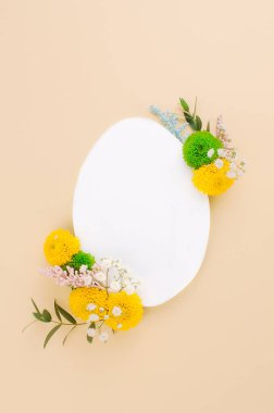 Mutlu Paskalyalar. Beyaz kağıttan paskalya yumurtası, bej arka planda çiçekler ve mesaj için boş alan. Üst manzara, düz uzanma.