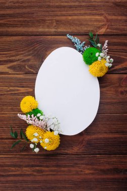 Mutlu Paskalyalar. Kırsal ahşap arka planda çiçekli beyaz kağıttan paskalya yumurtası ve mesaj için boş alan. Üst manzara, düz uzanma.