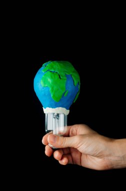 Dünya Saati konsepti: Plasticine Earth gezegen modeli olarak dekore edilmiş ve metin için boş alanı olan elektrik lambasını tutan kadın el.