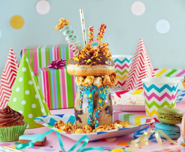 Çocukların parti konsepti: Çikolata manyağı, çikolatalı çörek ve çocukların parti masasında süslemeli karamelli patlamış mısır karışımı..