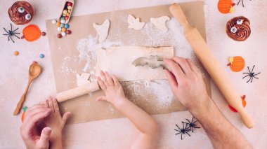 Baba ve çocuğun elleriyle yapılan Cadılar Bayramı kurabiyelerinin en üst görüntüsü.