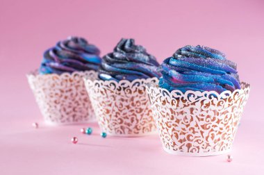 Galaksi koyu kremalı üç vanilyalı kek ve pembe arka planda ince kâğıt ambalaj kağıdı.