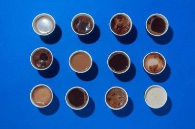Bir sürü kahve fincanı, farklı tipte kahve, kapuçino ve mavi arka planda macchiatoon ve mesaj için boş alan. Üst görünüm, düz görünüm.