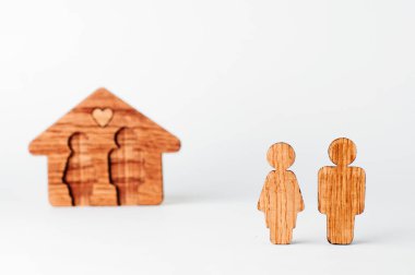 Beyaz arka planda evin önündeki tahta erkek ve kadın figürleri. Çift figürlerine odaklan, metin için boş alan.