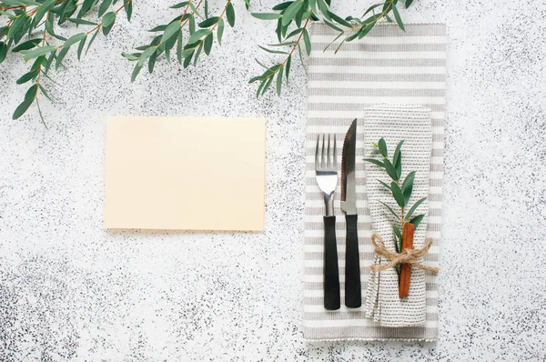 Holiday elegant table setting with linen napkin, sprig and cinnamon and empty card with blank space for text. Top view, flat lay.