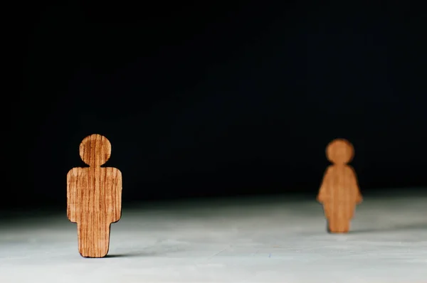 Wooden figures of man and woman on black background with blank space for text. Focus on male figure.