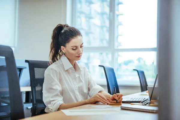Ofisteki dizüstü bilgisayarda çalışan iş kadını.