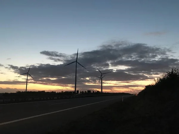 Wind farm and wind turbines with sunset and colorful sky and clouds