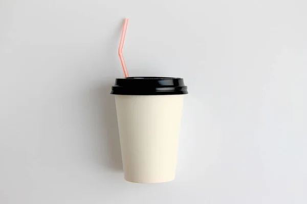 paper cup with a black lid and a drinking tube on a light background