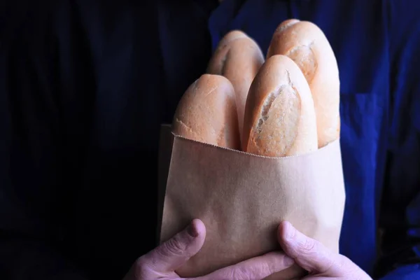 french baguettes in a paper bag in male hands