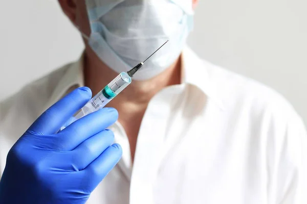 Syringe and hand closeup. The concept of vaccination, filling the drug into the syringe. Doctor background