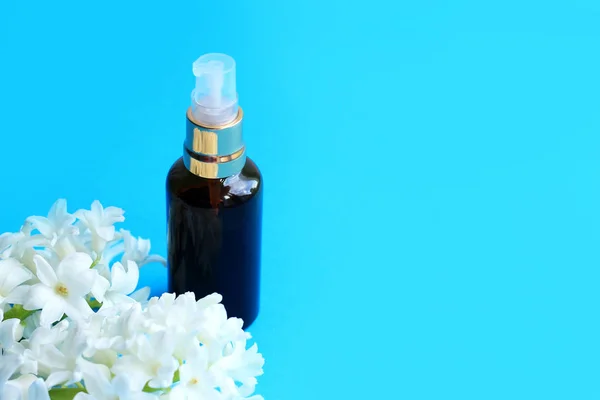 Bottle cosmetic with flowers on blue background