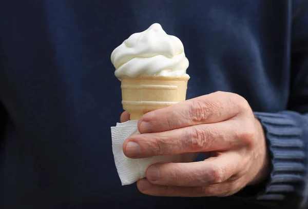 White ice cream cone melting in a man\'s hand, hand in a long sleeve sweater.