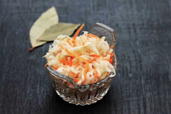 Fermented cabbage. Vegan food. Sauerkraut with carrot and spices in bowl on the dark background. Trend food.