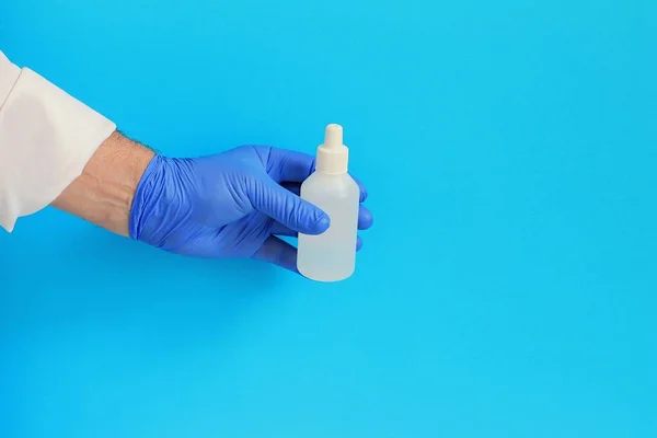 Medicine bottle in doctor hand, Medical vial in doctor\'s hand in blue glove, isolated on blue background.