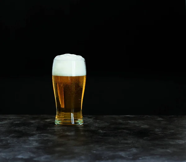 Oktoberfest beer festival concept. Cold beer with foam in glass on dark background, copy space.