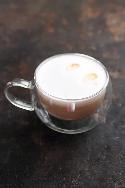 Cappuccino coffee with milk foam transparent glass cup.