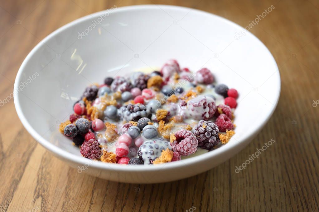 Frozen fruits with granola and yogurt, healthy fruit breakfast.