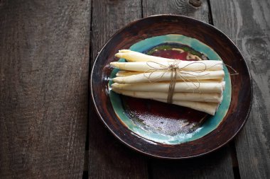 Beyaz kuşkonmaz. Bir seramik tabak sebze bir demet.