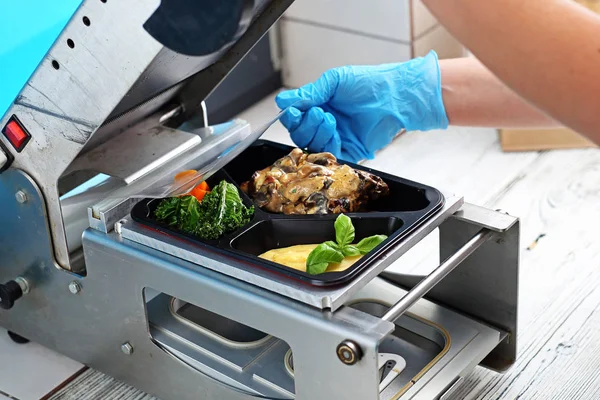 Yiyecekleri tepsilerde paketliyor. Restoran paket yemekleri