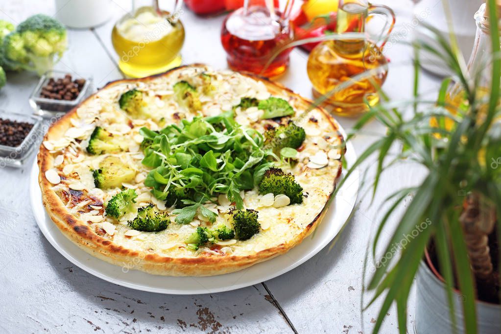 Vegetarian pizza with broccoli, garlic sauce, vegan mozzarella cheese and almonds