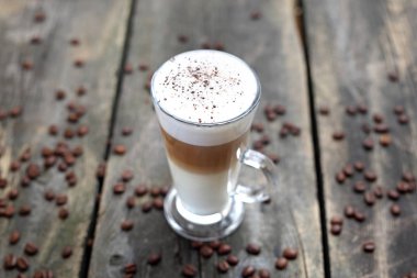 Caffe latte, ahşap bir arka plan üzerinde köpüklü süt ve süt köpüğü ile bir bardak kahve.