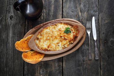 Patates, et ve peynirli güveç. Pişirme kabında servis edilir..