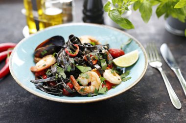 Deniz mahsullü makarna. Karides, midye ve ahtapotlu kara makarna. İştah açıcı yemek. Yemeği servis etmeyi öneriyorum. Mutfak fotoğrafçılığı.