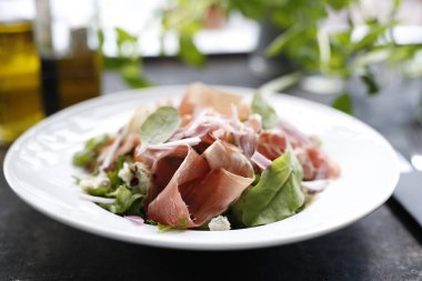 Parma jambonlu salata, domates, sarı pancar kökü ve salata sosu. Beyaz tabakta servis edilen aperatif tabağı. Mutfak fotoğrafçılığı.