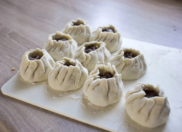 The process of making home-made dumplings. Raw homemade dumplings on a wooden board. Molding dumplings. — Stock Photo, Image