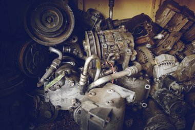 Garajda paslanmış metal araba parçaları var. Eski, modası geçmiş motor, yakın çekim, motorlu araba arızası. İşe yaramaz, yıpranmış fren diskleri ve diğer parçalar..