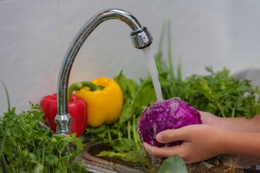 Suya meyve ve sebze sıçratıyorum. Taze meyve ve sebzeler, sağlıklı ve doğal bir gıdaya dönüşmeden önce yiyecekleri yıkamanın tasviri..