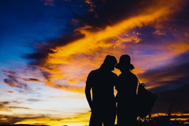 Gün batımında siluetler, gün batımında birbirine aşık romantik çiftler, tatilde ya da balayında aşık genç erkek ve kadın siluetleri..