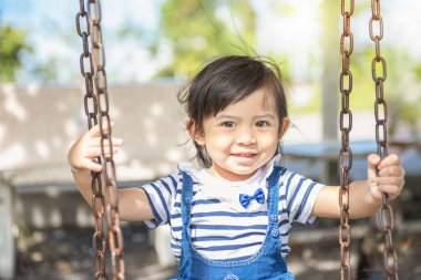 Küçük tatlı Asyalı kız oyun parkındaki oyuncunun keyfini çıkarıyor. Çocuk parkında oynayan küçük kız. 