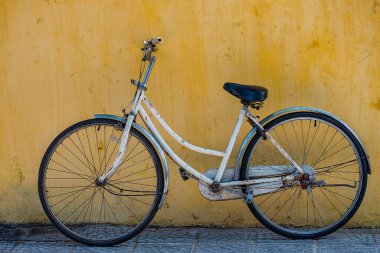 Arka planda sarı duvar olan eski bir bisiklet.