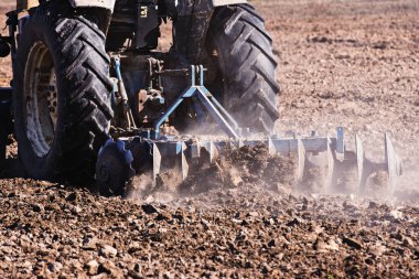 Tarım, traktör, ekili ekiciyle toprağı hazırlıyor. Tarım arazilerindeki tarım çalışmalarının ilkbahar başlarında tohumlama faaliyetlerinin bir parçası olarak..