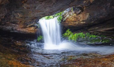 Panoramik fotoğraf manzarası tropikal bölgede saklı şelale ormandaki güzel şelale ormandaki büyüleyici şelale ve su bir delikten akıyor..