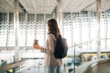 Arkada nansıyla havaalanındaki kız, kahve fincanıyla.