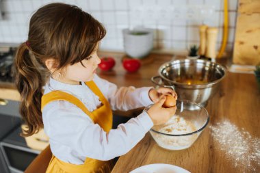 Küçük kız mutfakta bir pasta pişirme.