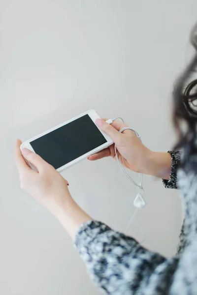 Beyaz akıllı telefonu elinde tutan genç bir kadın..