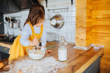 Küçük mutlu kız mutfakta hamur karıştırma.