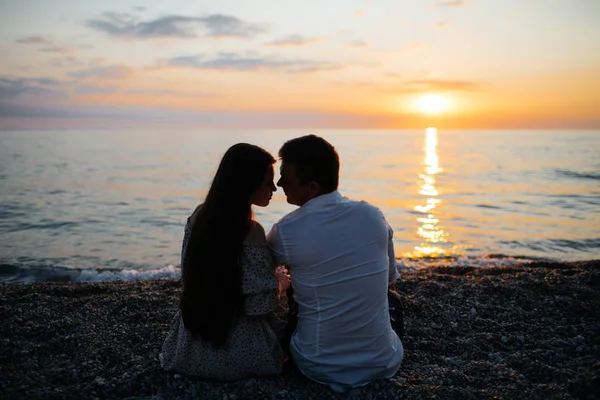 Foto de jovem casal amoroso na praia ao pôr do sol . — Fotografia de Stock