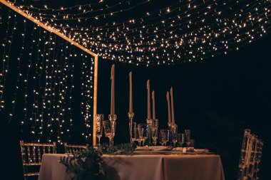 Mumlar ve çelenkler ile servis akşam yemeği masası.